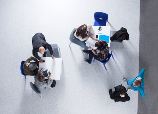 Two groups of office workers collaborating at different tables.